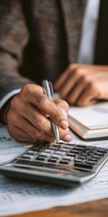 Person calculating finance using calculator and pen at desk