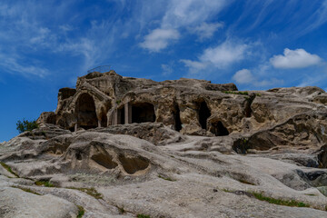 Ancient Uplistsikhe rock caves under dramatic blue cloudy sky