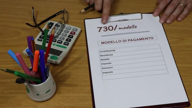 Form filling taxes 730 in Italy, unified payment. A man's hand, an office worker, indicates the correct completion with copy space. Looking Up.