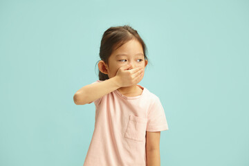 Giggling Child Hand-Covering Mouth and looking aside, has shyness after said, standing over blue...