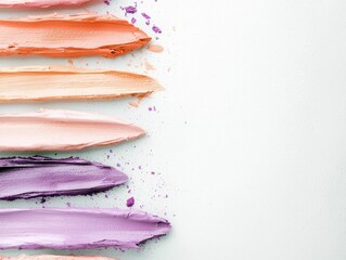Close-up of colorful makeup swatches on a white background. Various shades of lipstick and eyeshadow are displayed in textured strokes, creating a vibrant flat