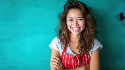 A joyful woman wearing a striped apron smiles happily against a vibrant teal background, highlighting the themes of happiness, creativity, and culinary passion in everyday life.