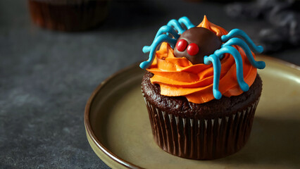 Delicious chocolate Halloween cupcake with vibrant orange frosting and fun blue candy spider decoration