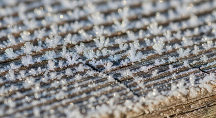 Close up of frost crystals on wood surface in winter sunlight creating textured pattern