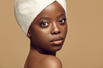 Beautiful African girl in hair drying towel looks to camera.