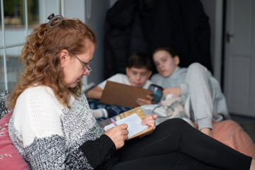 Mom and children at home playing the board game sea battle, weather is bad outside and they are sitting at home and enjoying communication and playing together