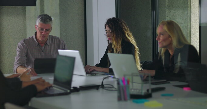 Team working independently on laptops in modern office meeting room with digital display and collaborative environment - Powered by Adobe