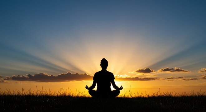 Silhouette of person meditating in lotus pose at sunset with sunburst meditation yoga