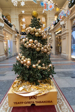 Russia. Moscow. GUM store. Golden-decorated Christmas tree with Theatre of Oleg Tabakov branding, displayed in elegant shopping arcade