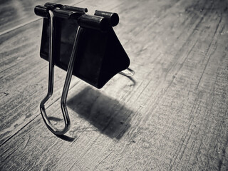 Pince à reliure sur une table en bois monochrome.