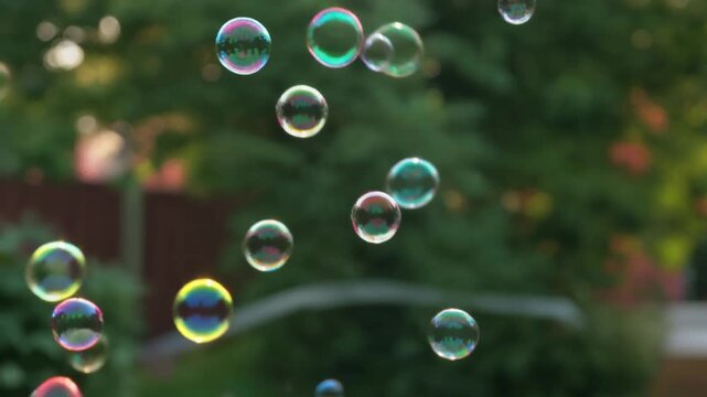 Children&rsquo;s soap bubbles drifting in air, colorful June backyard ambiance.