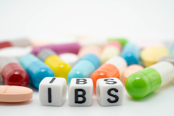 IBS Irritable bowel syndrome word with pills and capsules medical drug.