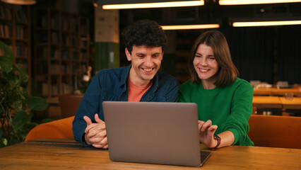 Colleagues brainstorming new ideas using laptop in modern cafe