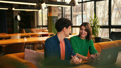 Colleagues brainstorming new ideas using laptop in modern cafe