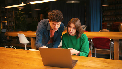 Colleagues brainstorming new ideas using laptop in modern cafe
