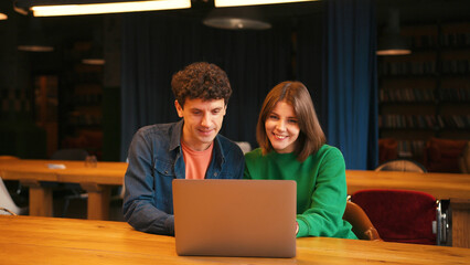 Colleagues brainstorming new ideas using laptop in modern cafe