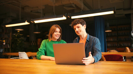 Colleagues, smiling woman and man having video conference meeting on laptop in modern office