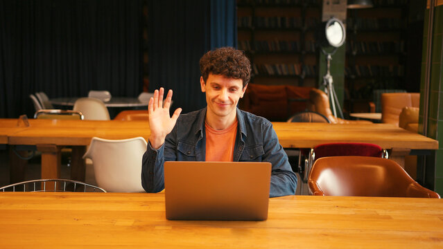 Professional man participating in a business video conference call waving hand