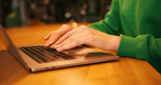 Woman's hands typing on laptop keyboard wooden desk, online technology concept