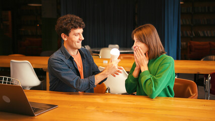 Smiling woman and man brainstorming new idea with light bulb, brainstorming concept