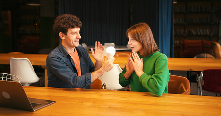 Smiling woman and man brainstorming new idea with light bulb, brainstorming concept
