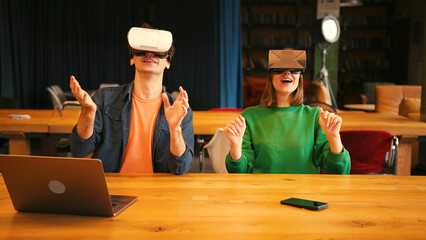 Young couple interacting with augmented reality in vr goggles in modern office