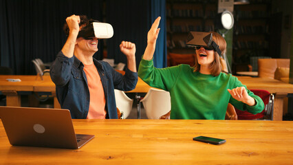 Young couple interacting with augmented reality in vr goggles in modern office