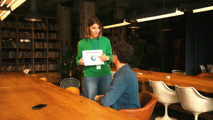 Businesswoman showing project statistics to male colleague in modern coworking