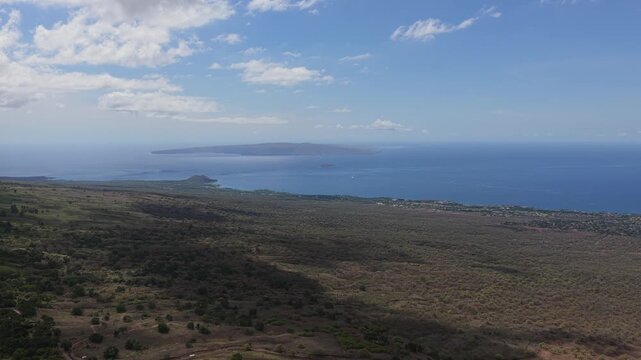 A smooth, sideways drone flight over the hills of UpCountry Maui, revealing a vast panorama of the South Maui coast and the islands of Molokini and Kahoʻolawe in the distance.