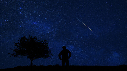 Fototapeta premium Silhouette of a man and countryside under the Milky Way stars.