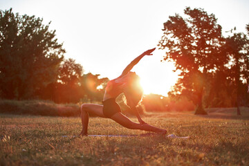 Woman practicing yoga and stretching in the park on a hot sunny summertime day.