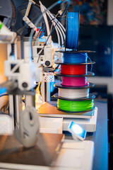 row of colorful 3d printing filament PLA material on environmentally friendly and recyclable paper cardboard spools on black carbon fiber background. modern FDM printer technology concept