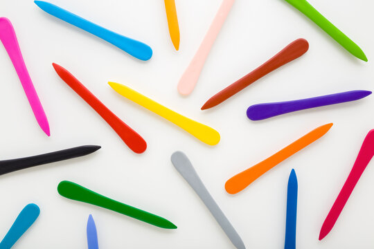 Pattern of colorful wax crayons on white table background. Closeup. Top down view.