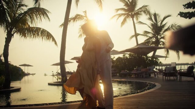 Romantic couple affectionately dancing together during a beautiful tropical sunset at a luxury resort