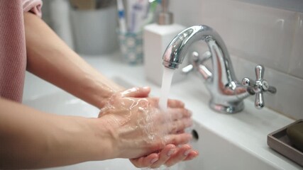 An unrecognizable woman washing her hands in a sink. Concept hygiene routine.