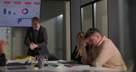 Upset manager blaming employees during office meeting as team members react with shame and disbelief around boardroom table