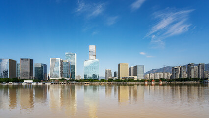 Obraz premium Modern city skyline with tall buildings reflecting in the water