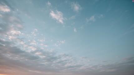 Obraz premium a serene image of a blue sky filled with soft, fluffy clouds. The sky transitions from a lighter shade to a deeper blue, creating a sense of peace and tranquility