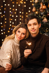 happy mother with son against the background of christmas tree and new year bokeh with sparklers