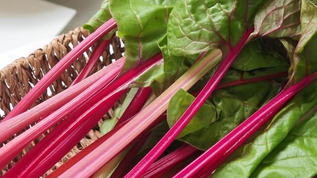  Swiss chard with bright red and orange stalks and green leaves in basket