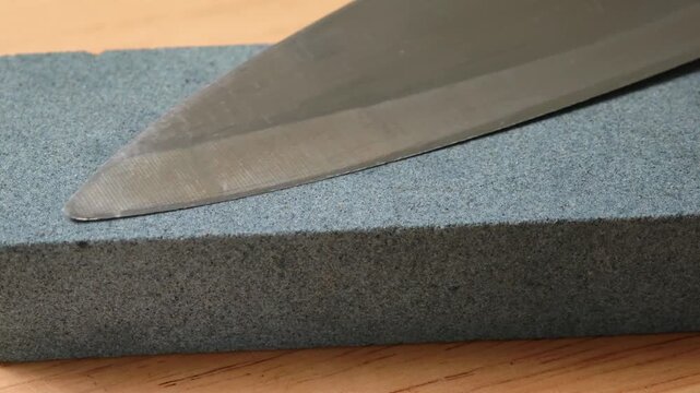 Sharpening Kitchen Knife With Water Whetstone On A Kitchen Table