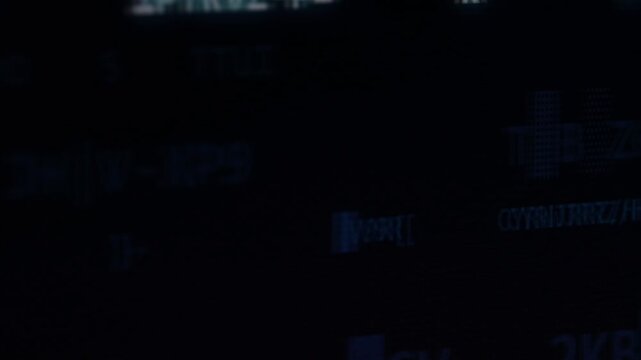 Dark digital screen with cryptic alphanumeric characters and coded visual elements.