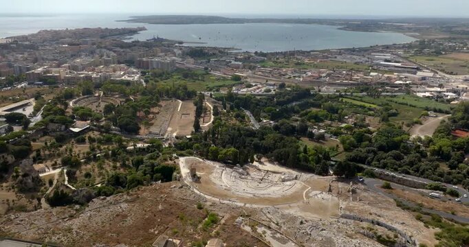 Panoramic aerial view of the Neapolis Archaeological Park, located in Syracuse, Sicily, Italy. In the background there's the modern city overlooking the gulf of the same name and the island of Ortygia