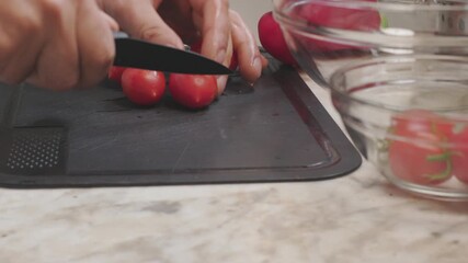A man cutting cherry tomatoes. Fresh vegetables on a cutting board. Healthy eating.