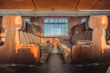 Sunlit Rusty Interior of a Vintage Railway Carriage with Worn Upholstery and Wooden Paneling