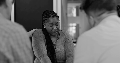 Fototapeta premium Woman crying during therapy session, receiving gentle touch from supportive group members in moment of deep vulnerability and shared empathy, black and white