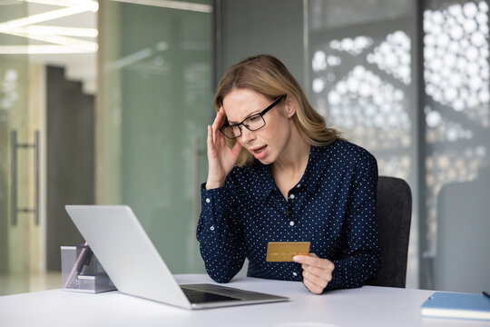 Woman feeling stressed and worried, having problems with a credit card trying to make an online payment on a laptop, highlighting issues like fraud, debt, or an unexpected payment problem