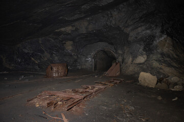 Abandoned underground mine tunnel with rusted ore cart and decayed rails