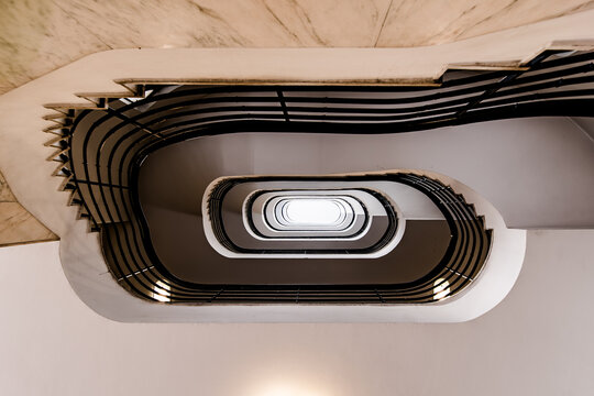 Oval Spiral Staircase Looking Up - Symmetrical Interior with Black Railings and Central Skylight