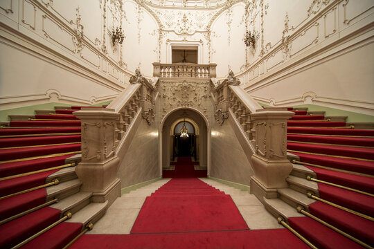 Grand ornate double staircase with red carpet in a historic Budapest palace interior